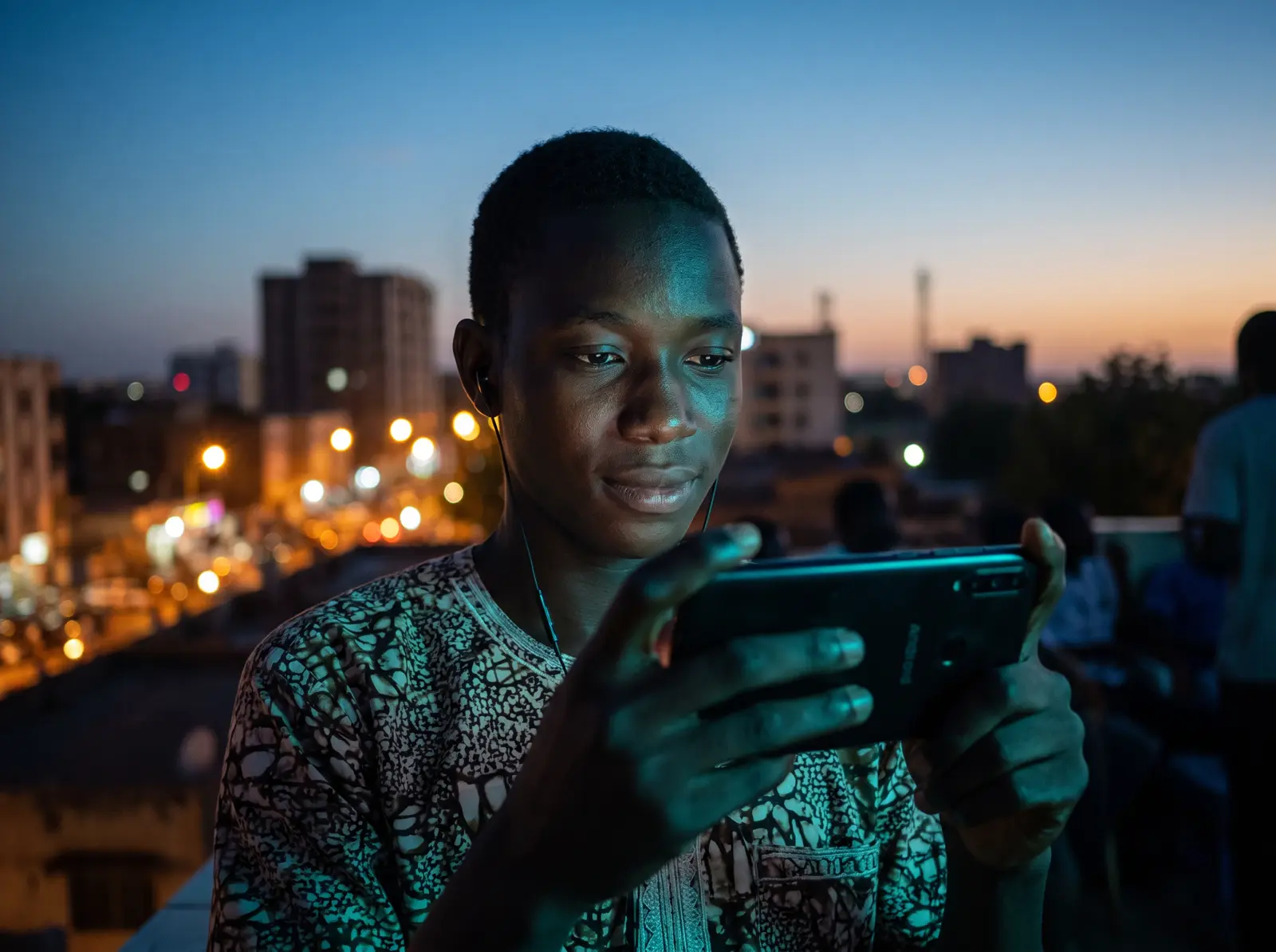 Un élève suit une leçon sur son téléphone, le soir, sur un toit de Bamako